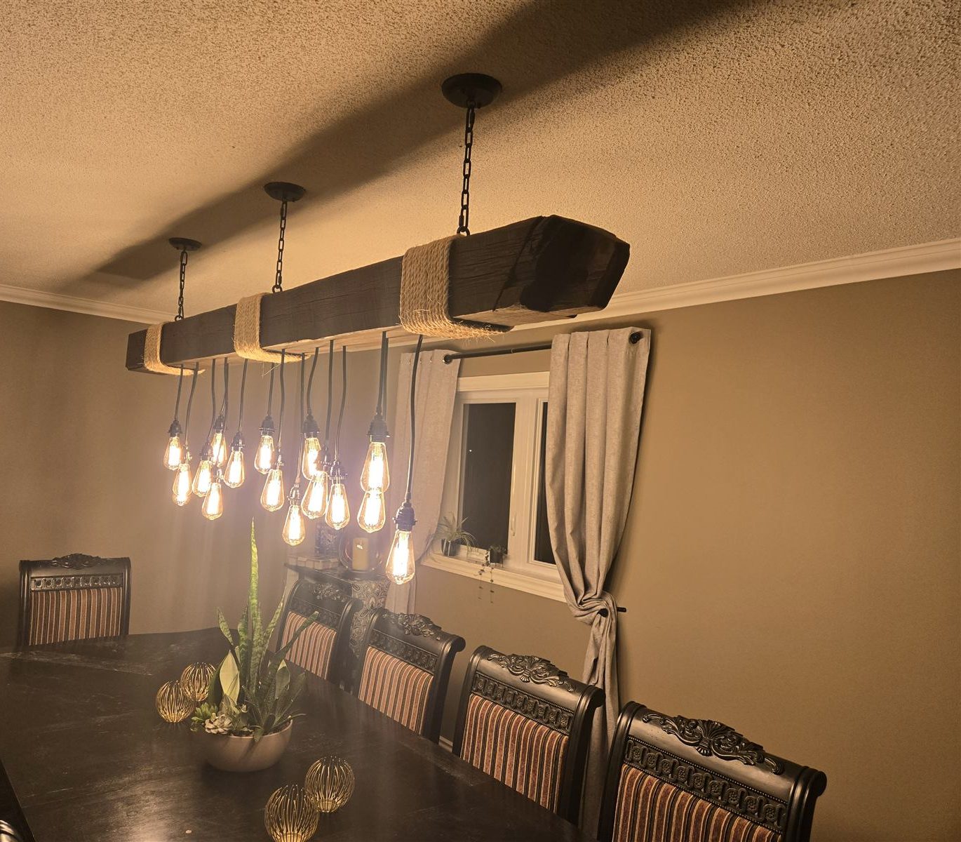 Custom wood light fixture with rope-wrapped bands and hanging Edison bulbs over a dining table